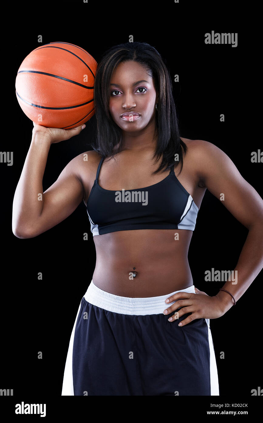 Junge sportliche schwarze Frau mit Basketball über Schwarz Stockfoto