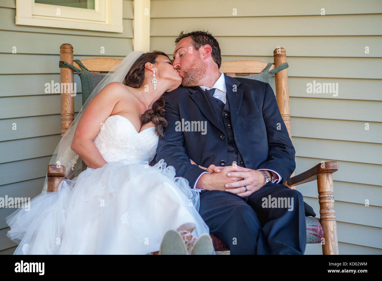 Brautpaar sitzen in einem Schaukelstuhl und tragen Ihre tuxedo Wedding Dress. Stockfoto