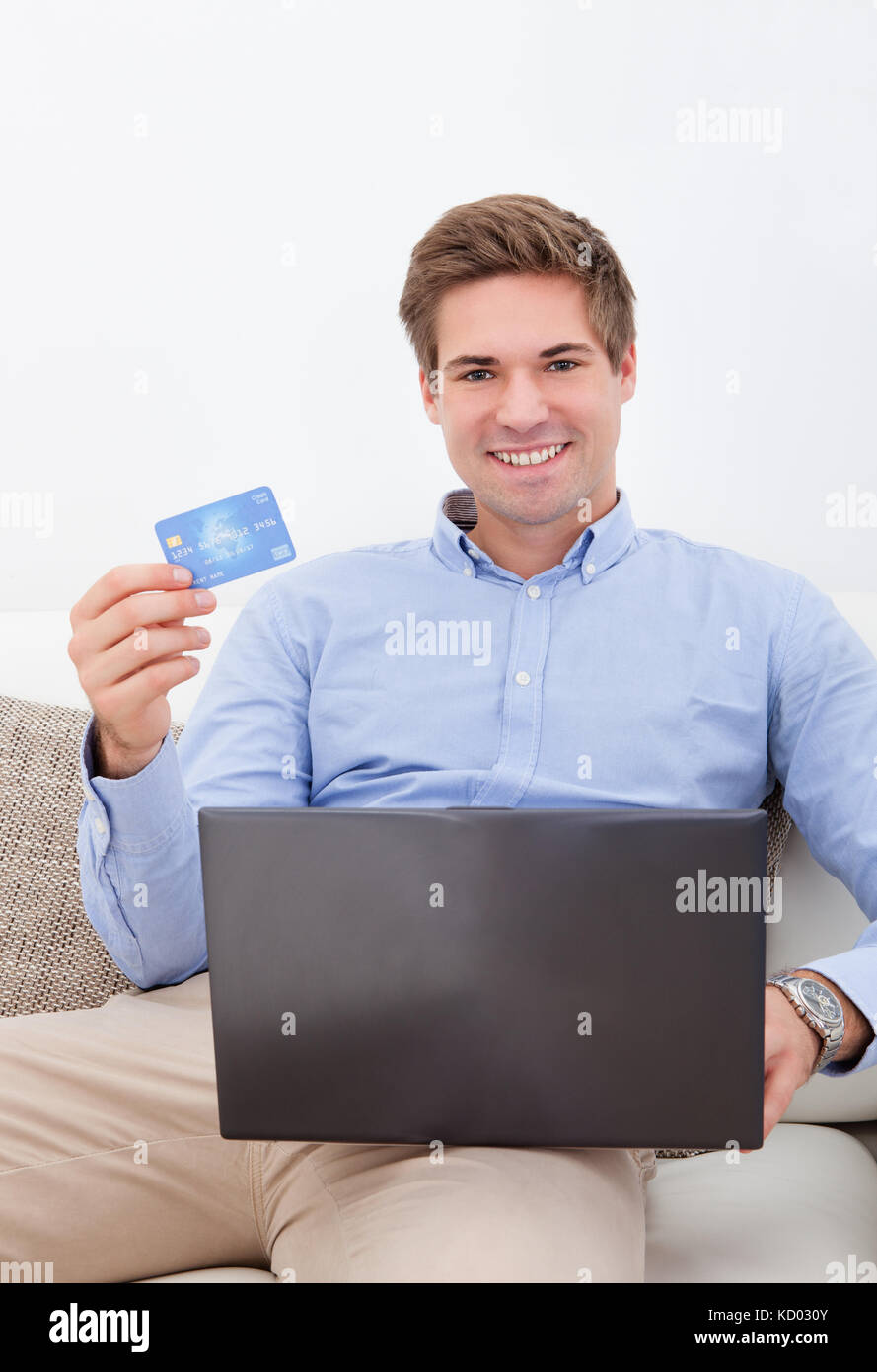 Mann, Online-Shopping von zu Hause mit Kreditkarte und Laptop Stockfoto