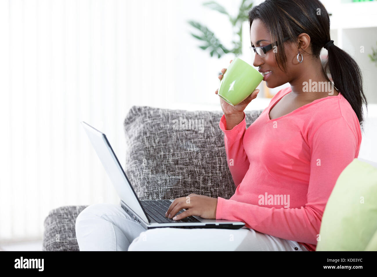 Schwarze Frau mit einem Laptop bei einem Kaffee in Ihrem Wohnzimmer Stockfoto