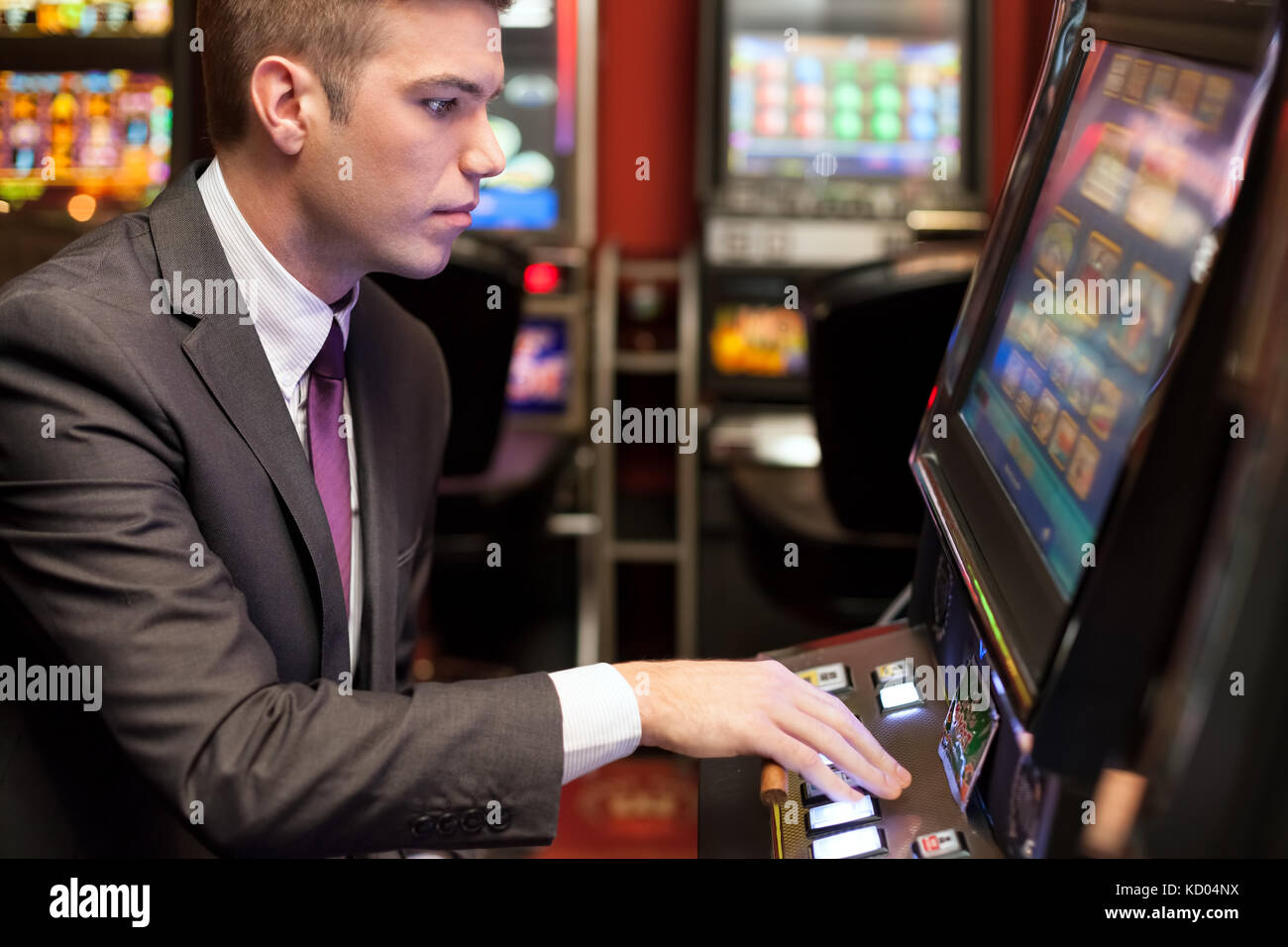 Junge schöne Männer spielen im Casino am Spielautomaten Stockfoto