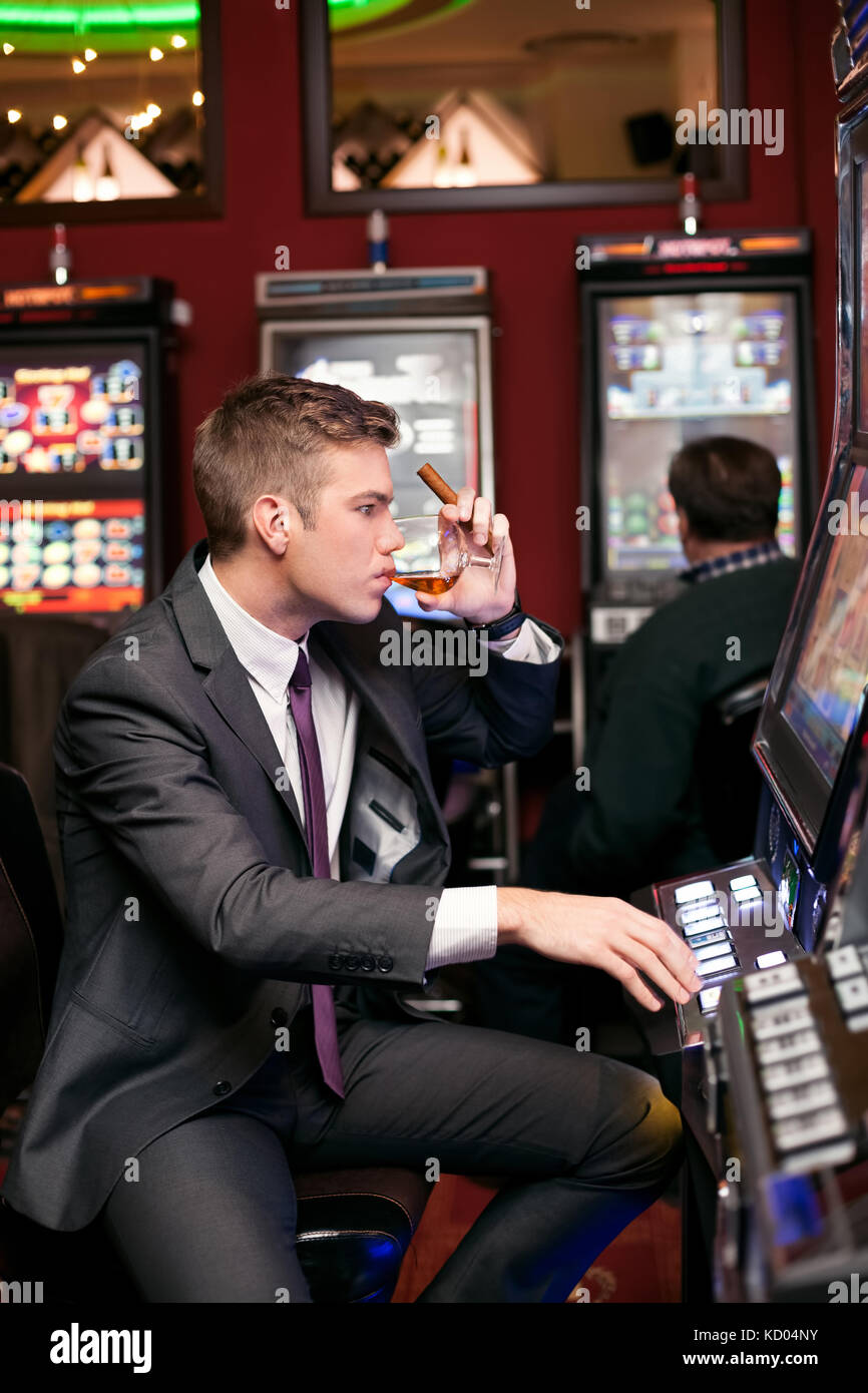 Schöner Mann in Spielen der Slot Maschine konzentriert wird Stockfoto