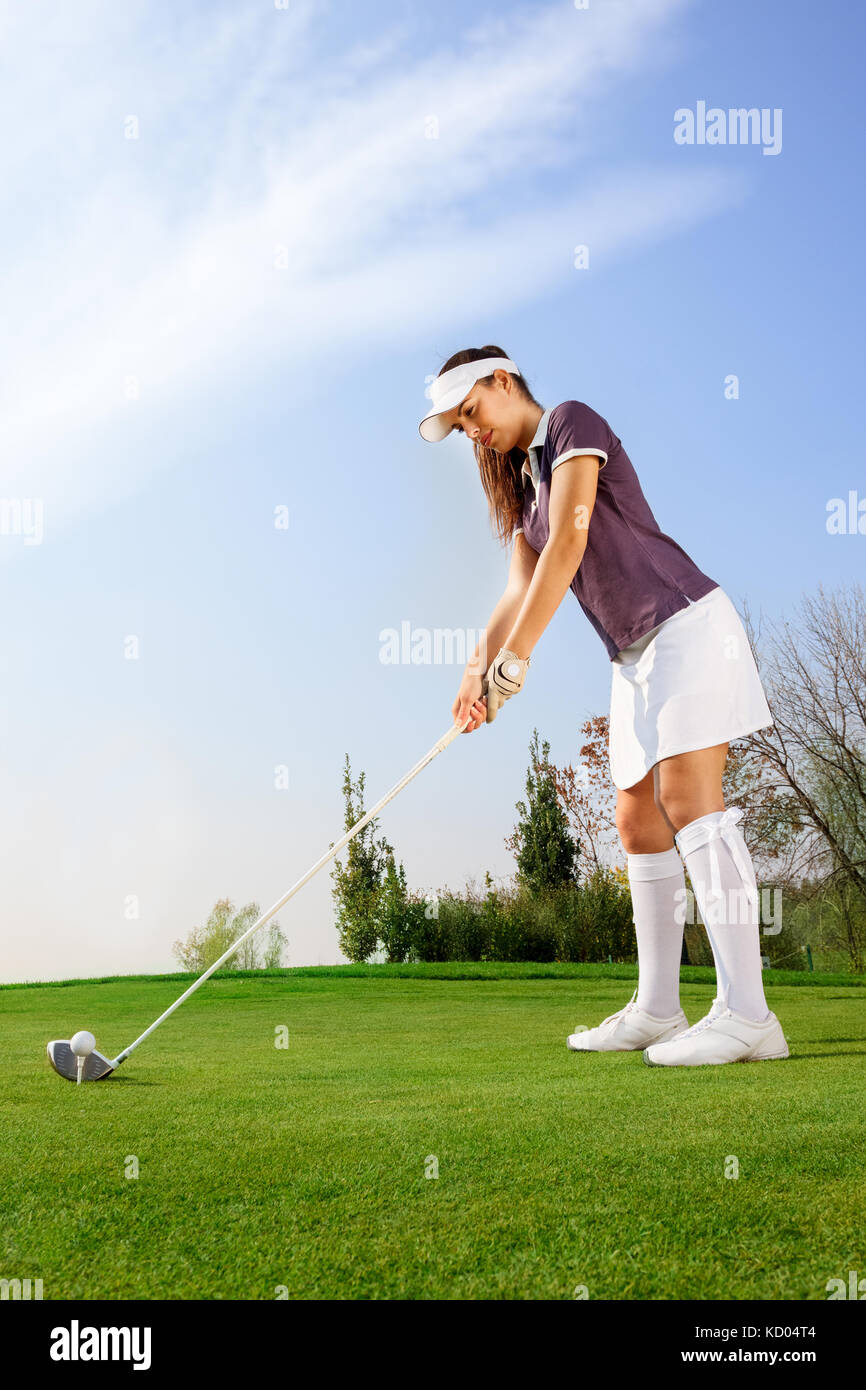 Weibliche Golfspieler fertig, den Ball auf den Golfplatz zu schlagen Stockfoto