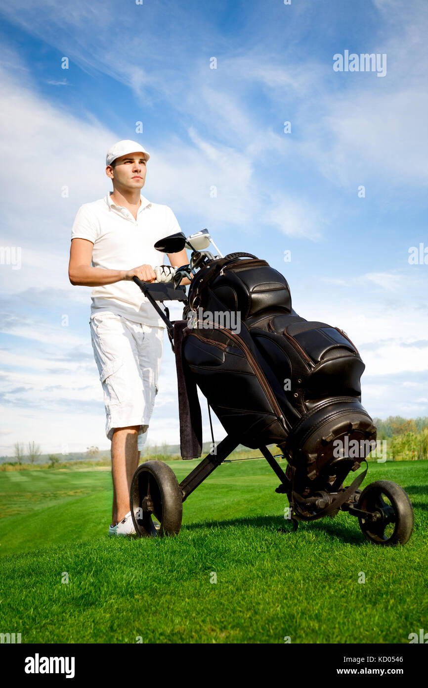 Hübscher junger Golfspieler auf dem Golfplatz mit seinen Vereinen und Tasche Stockfoto