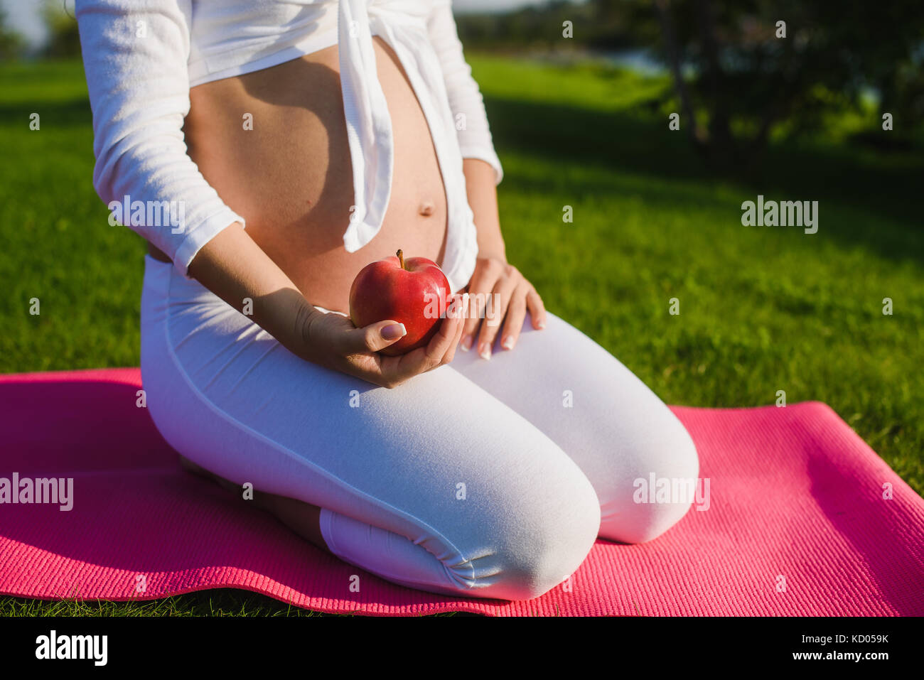 Schwangeren Yoga, ein Mädchen mit einem Apfel. Konzept der gesunden Ernährung. Stockfoto
