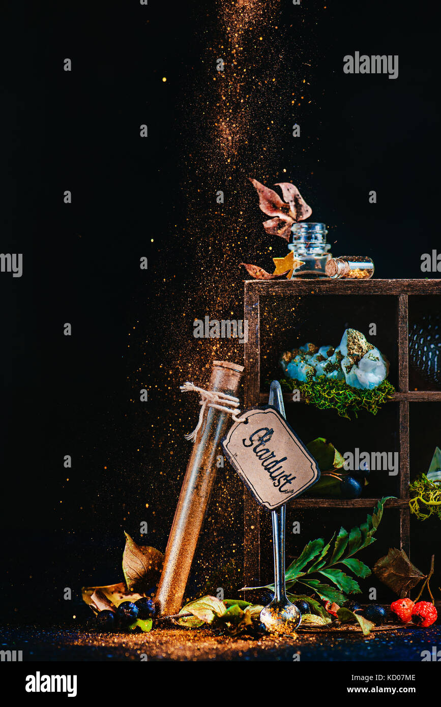 Mystische Stillleben mit einem Reagenzglas von Stardust und Holzgehäuse mit magischen Gegenstände und Trank Zutaten. Wizard oder Hexe Tabelle mit Pixie dust. Märchen Konzept mit dunklem Hintergrund und Kopieren. Stockfoto