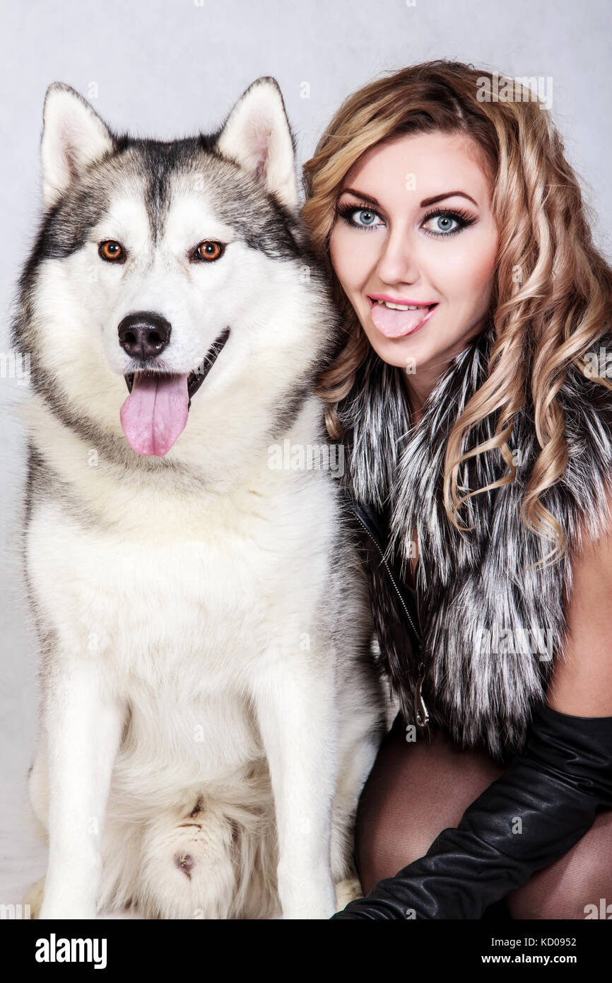 Schöne junge Frau mit einem Husky Hund über grauer Hintergrund Stockfoto