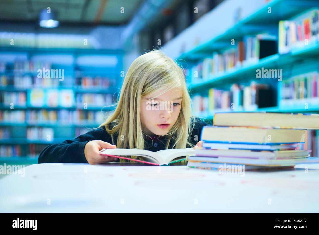 Kind, Mädchen in der öffentlichen Bibliothek mit Buch Stockfoto