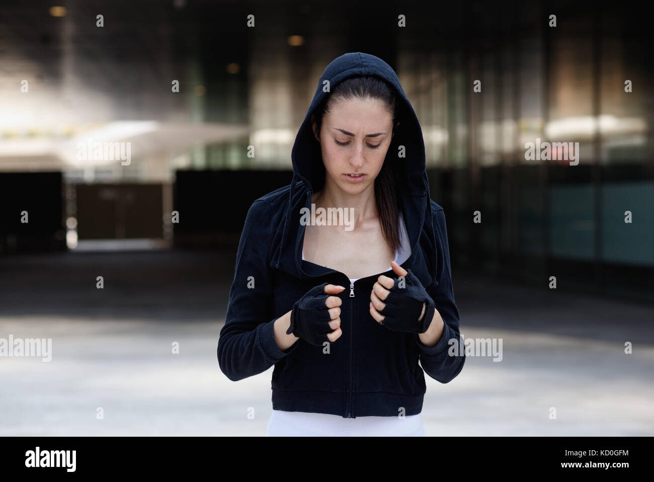 Junge Frau im Freien, tragen Kapuzen Top und fingerlose Handschuhe Stockfoto