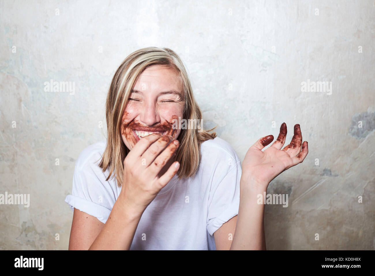 Portrait von Frau mit Schokolade an den Händen und um den Mund, Lachen Stockfoto