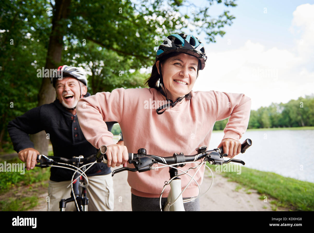Reifes Paar Radfahren am See, Lachen Stockfoto