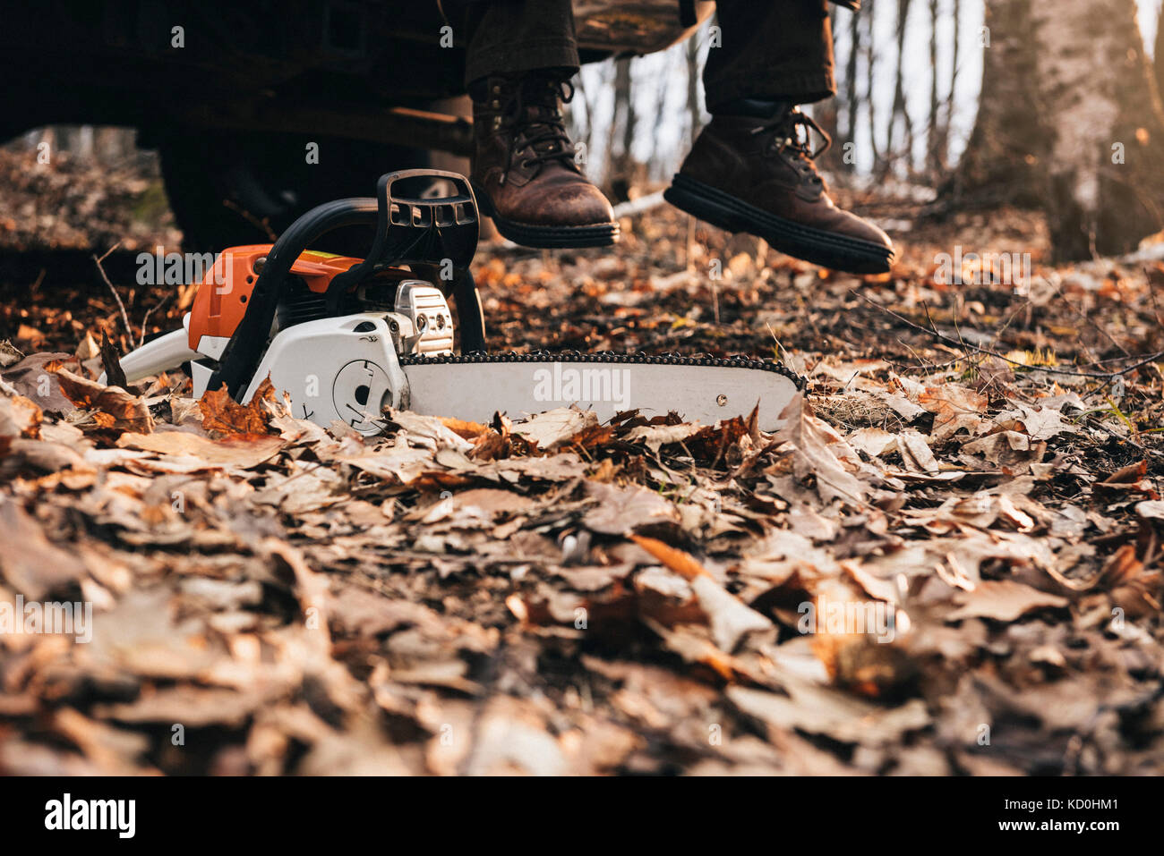 Mann in Stiefel und Kettensäge auf Herbst Waldboden Stockfoto