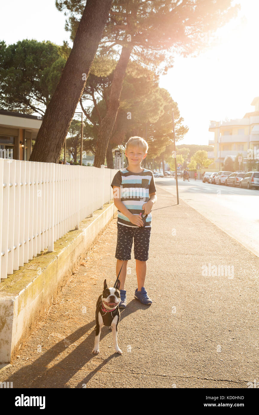Portrait der Junge mit Hund in der Straße an der Kamera schaut lächelnd Stockfoto