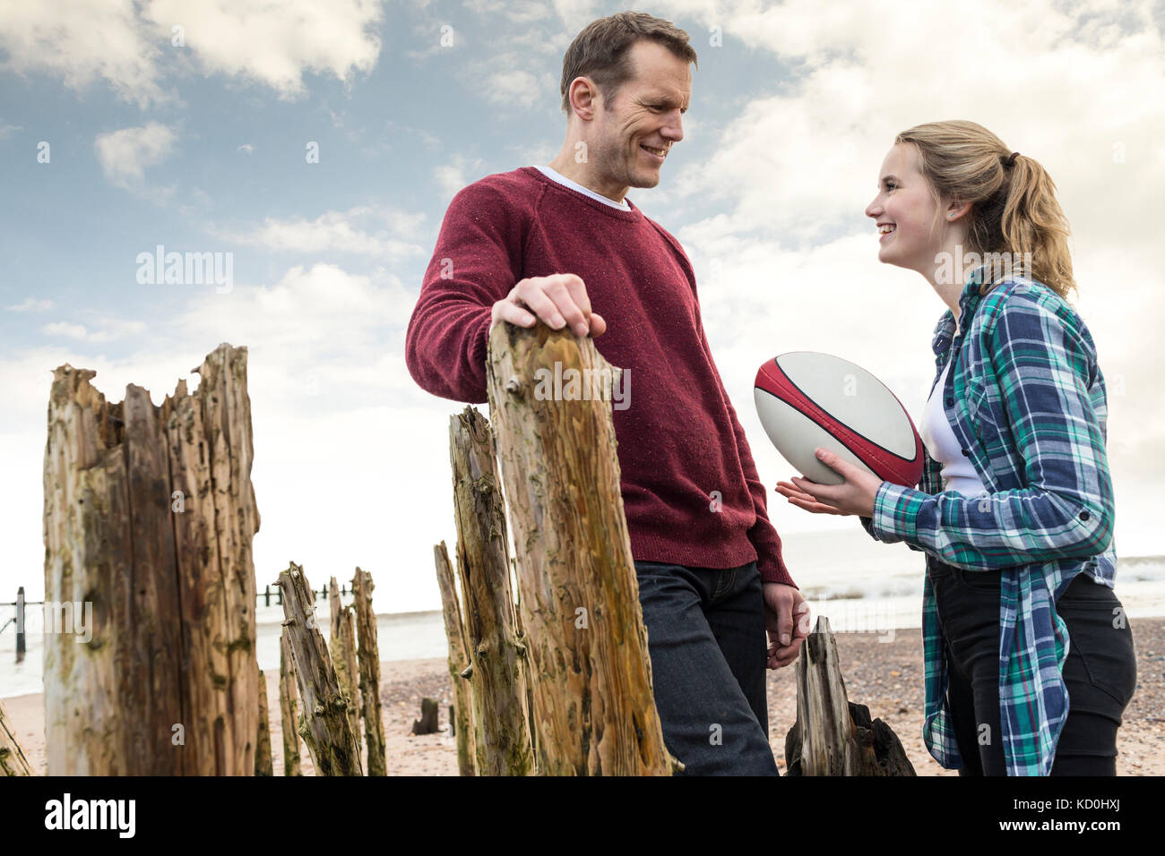 Vater und Tochter am Strand, reden, Tochter hält Rugbyball Stockfoto