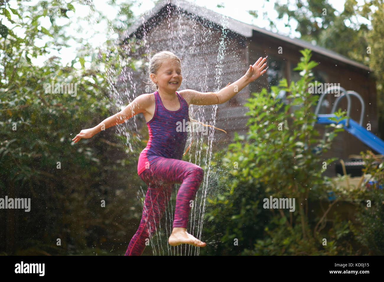 Mädchen über Garten Sprinkler springen Stockfoto