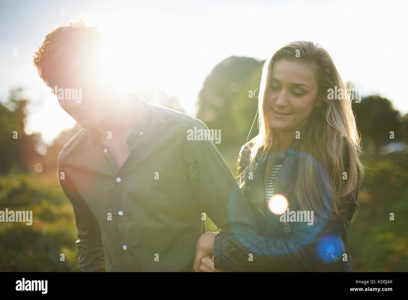 Junges Paar schlendern Arm in Arm im sonnenbeschienenen Feld Stockfoto