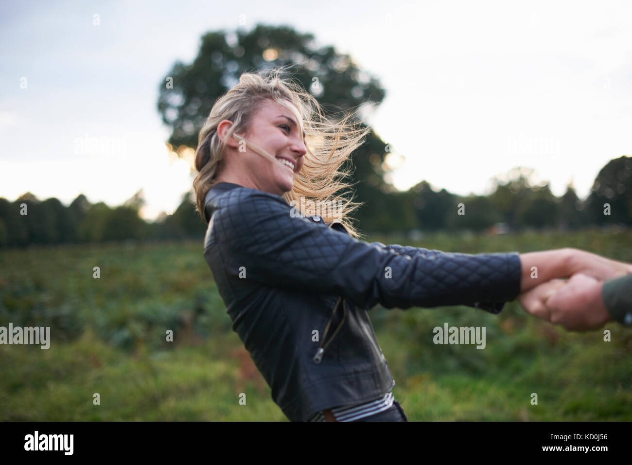 Die junge Frau mit Freund Hände und Drehen im Feld Stockfoto