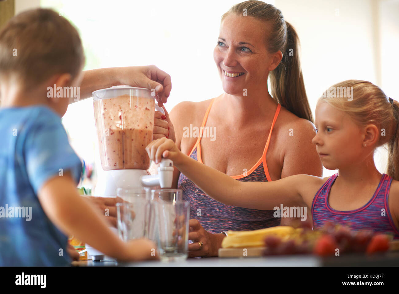 Reife Frau und Kinder mischen frischen Smoothie in der Küche Stockfoto