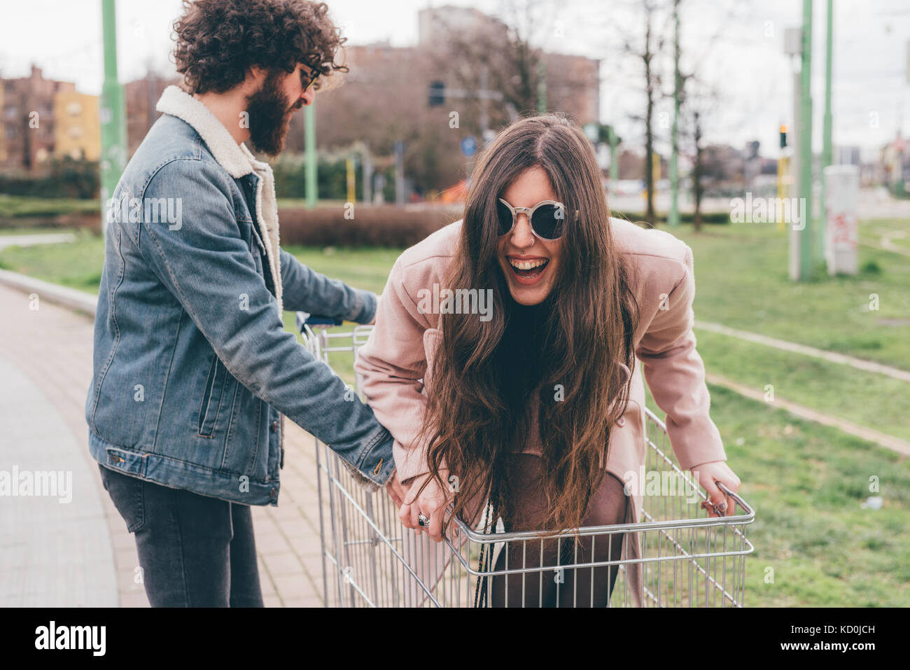 Junges Paar, draußen, Mann, Frau, im Einkaufswagen Stockfoto