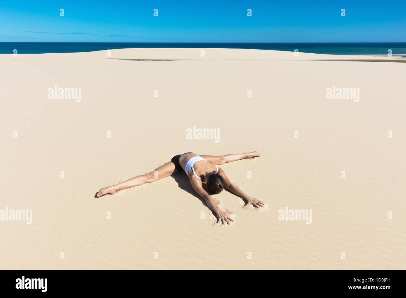 Frau am Strand in Yoga Position, biegen nach vorne tun die Splits Stockfoto