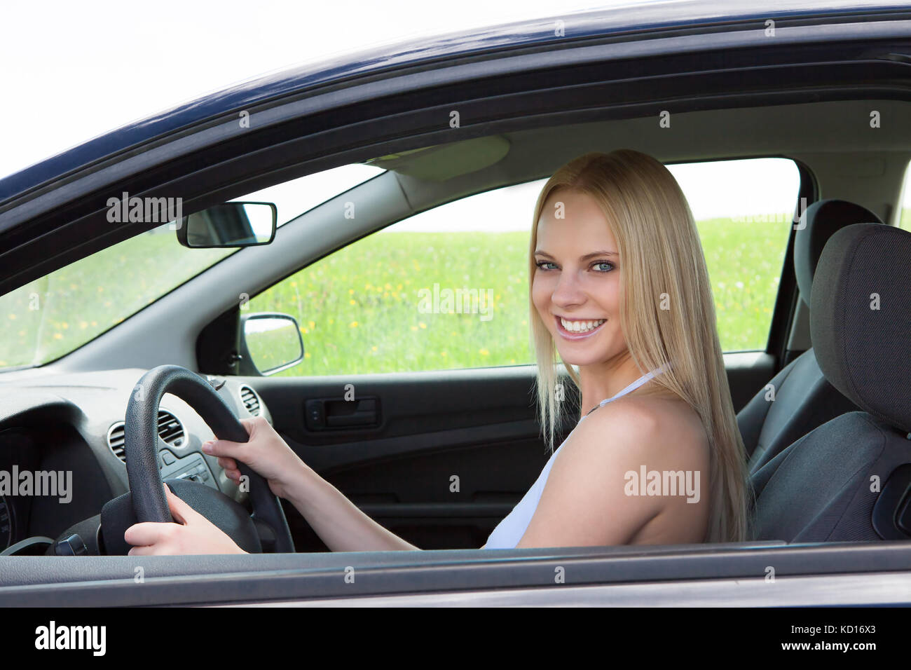 Glückliche junge hübsche blonde Frau, die Auto Stockfoto