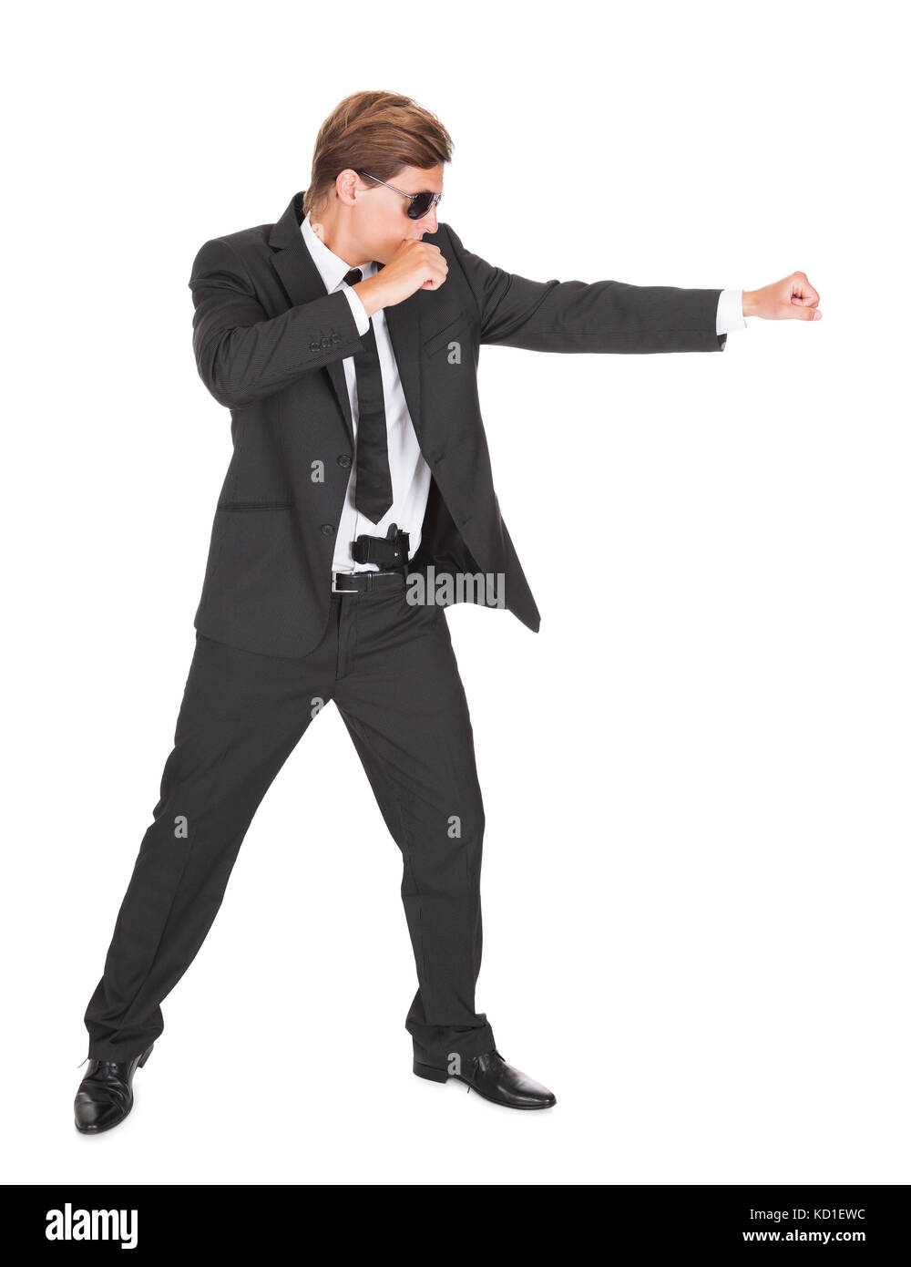 Junger Mann im schwarzen Anzug Stanzen auf weißem Hintergrund Stockfoto
