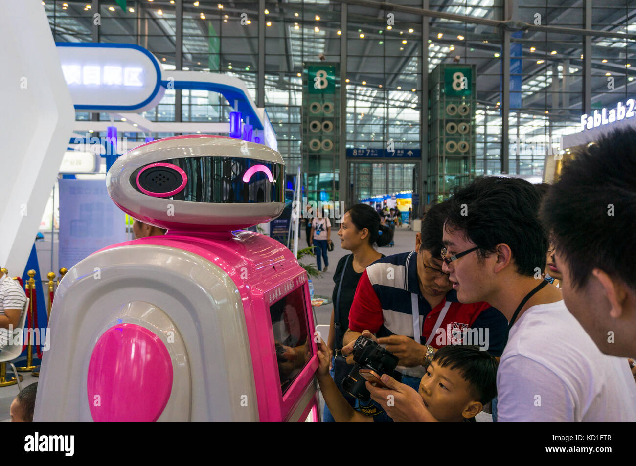 Neugierige Zuschauer machen Fotos von einem essen und trinken Service Roboter Teekocher Messe in Shenzhen, China Stockfoto