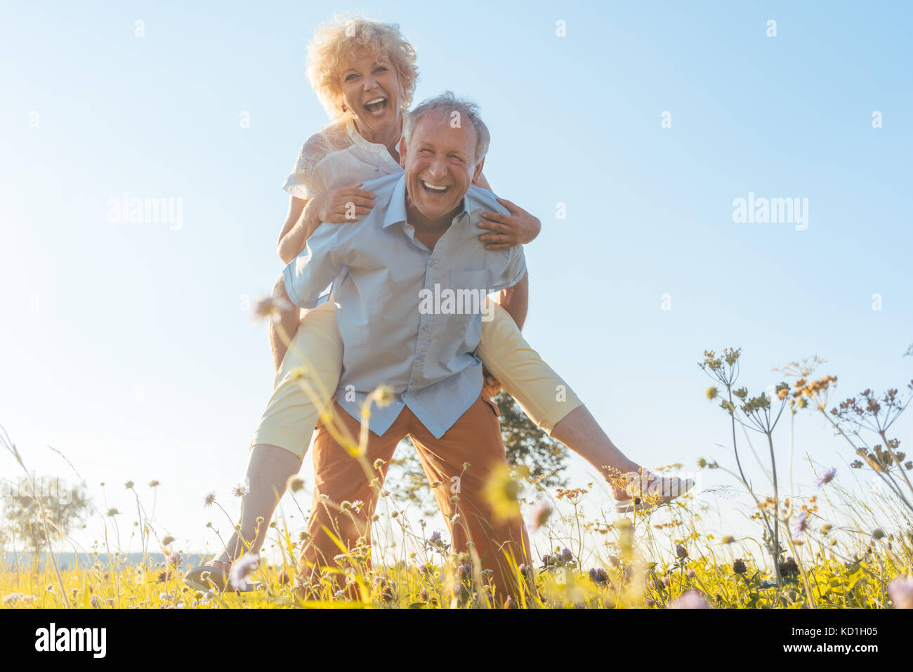 Gerne älterer Mann Lachen, während sein Partner tragen auf dem Rücken Stockfoto