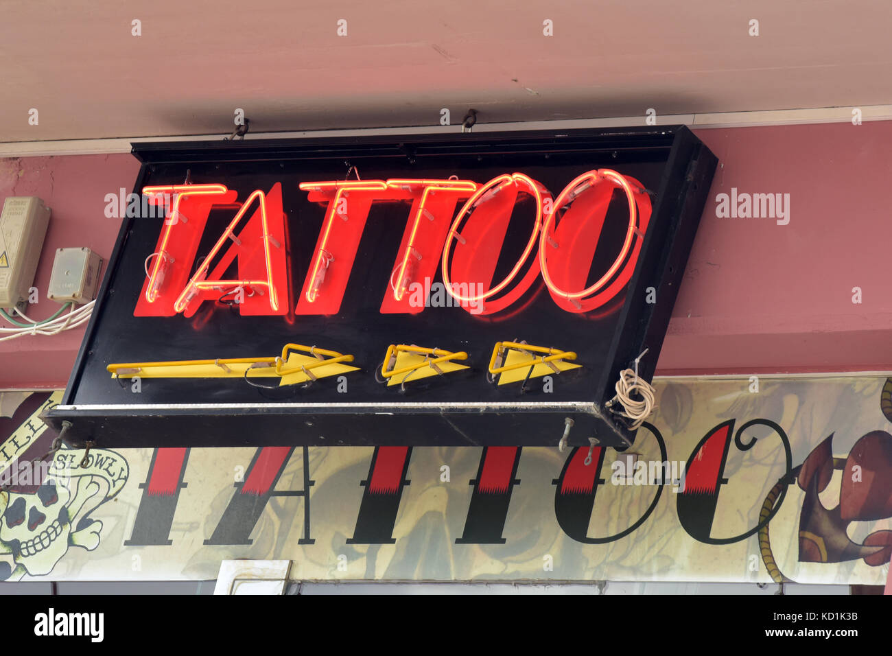 Ein Neon oder Leuchtreklame Werbung Tattoo mit einem Pfeil angezeigt, der die Richtung des Studio, Tätowieren und tattooists Salons und Studios. Stockfoto
