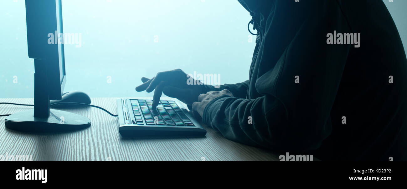Hooded Computerhacker Network Hacking. Männchen mit schwarzen mittels Computer für Identitätsdiebstahl oder andere kriminelle Online-aktivitäten Hoodie. Stockfoto