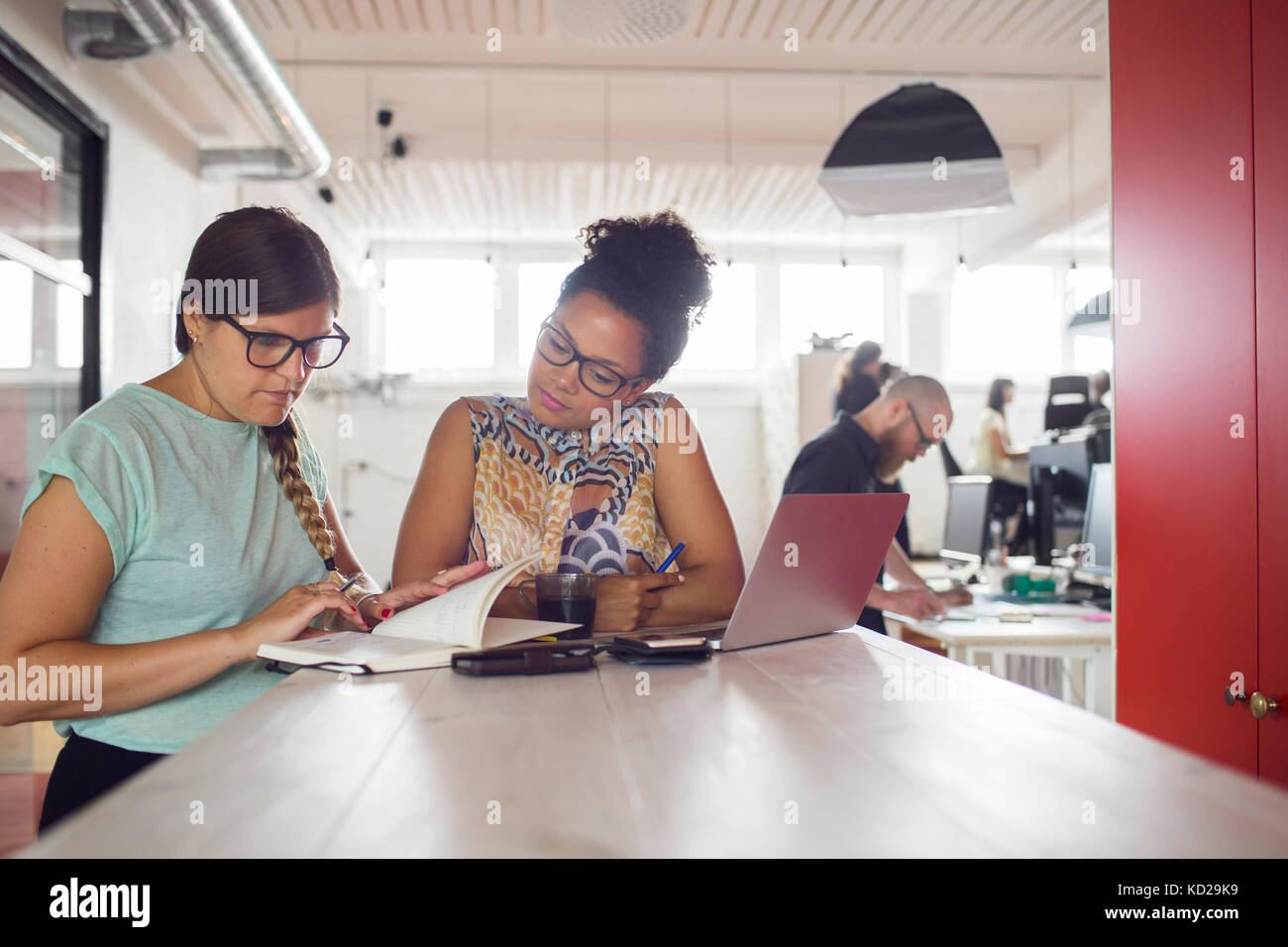 Frauen, die durch die Tabelle im Büro, Mitarbeiter im Hintergrund Stockfoto