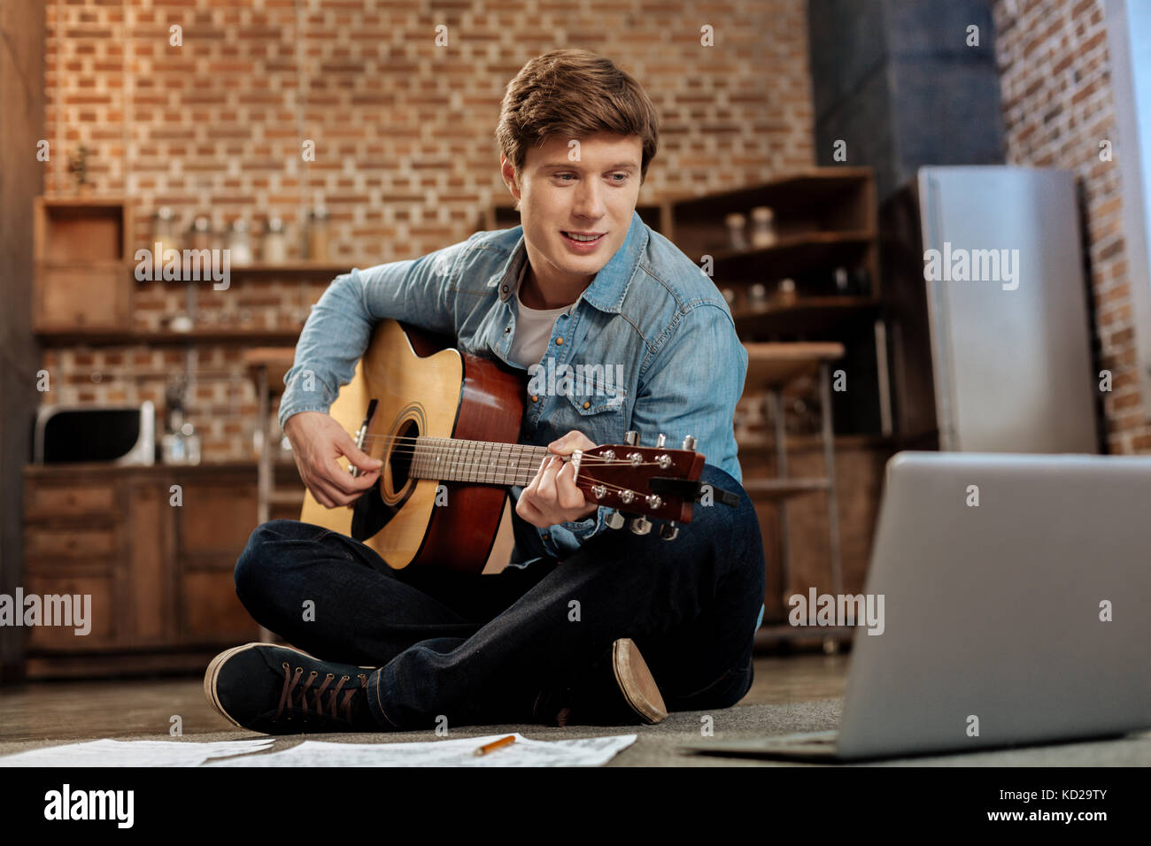 Charmanter Mann aufpassen spielen Guitar Tutorial Stockfoto