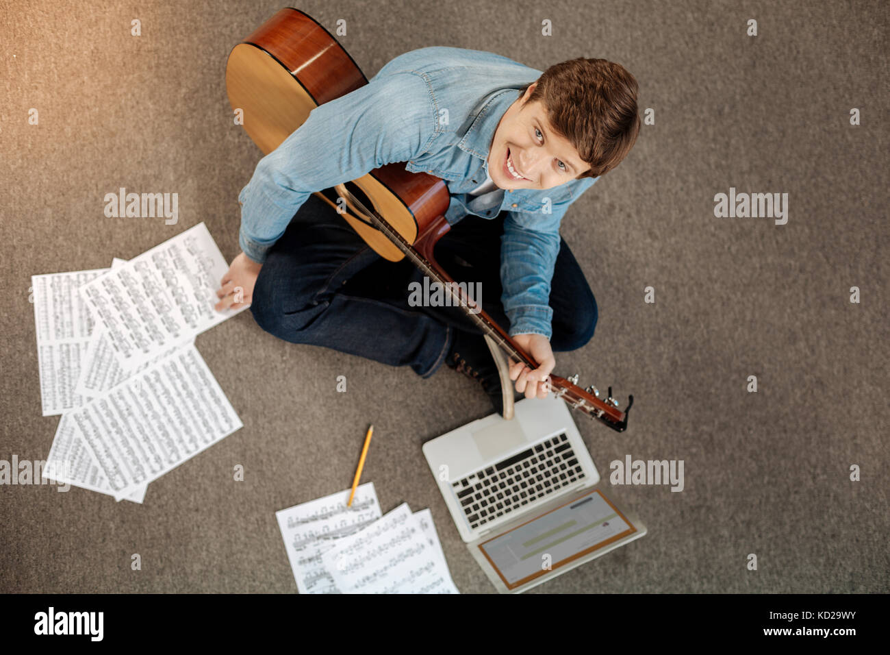 Blick von oben auf die jungen Mann mit Gitarre lächelnd an Kamera Stockfoto