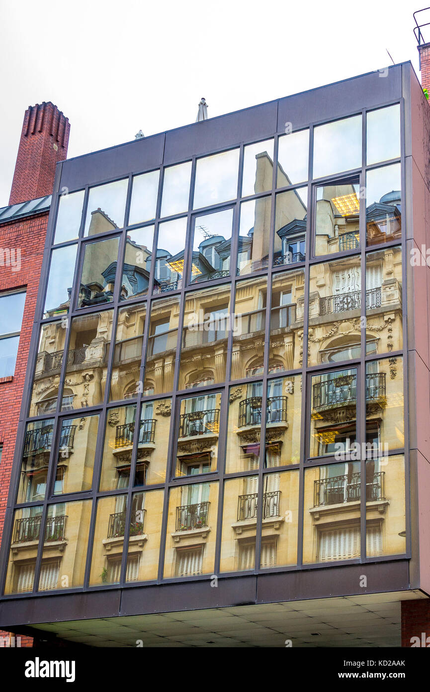 Schöne Apartments in einer Pariser Straße spiegeln sich in modernen Fenstern wider. Stockfoto