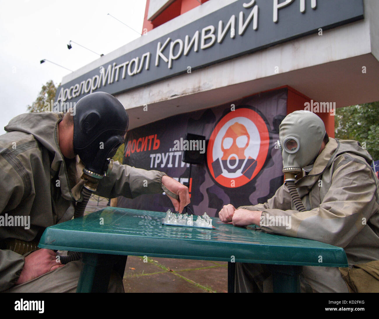 Kryvyi Rih, Ukraine - 9. Oktober 2017: Zwei Männer kleideten Gasmasken auf Gesichtern, die Schach spielen in der Nähe von ArcelorMittal Kryvyi Rih PJSC-Markendenkmal bei Protesttreffen gegen Luftverschmutzung Credit: Dmytro Aliokhin/Alamy Live News Stockfoto