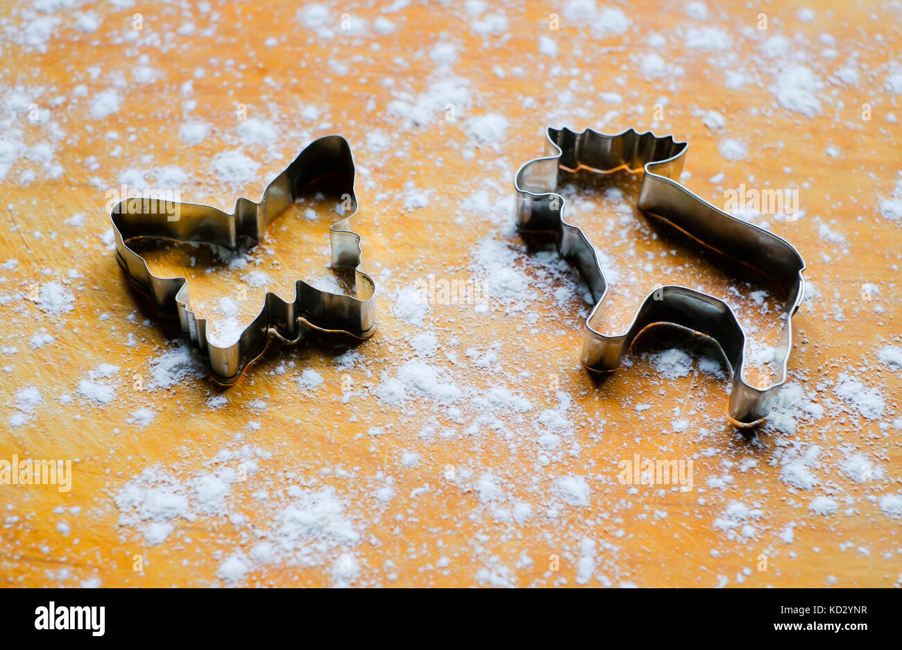 Metall Formen (Werkzeuge, Messer) für Ingwer Cookies in der Form von Elk oder Elche und Schmetterlinge auf Holzbrett, bestreut mit Backpapier Mehl. Stockfoto