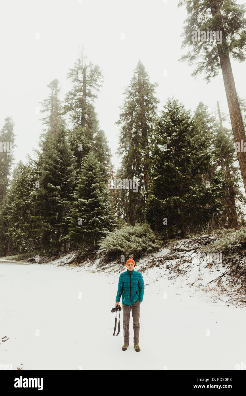 Porträt der jungen Mann mit Kamera im verschneiten Wald, Sequoia National Park, Kalifornien, USA Stockfoto