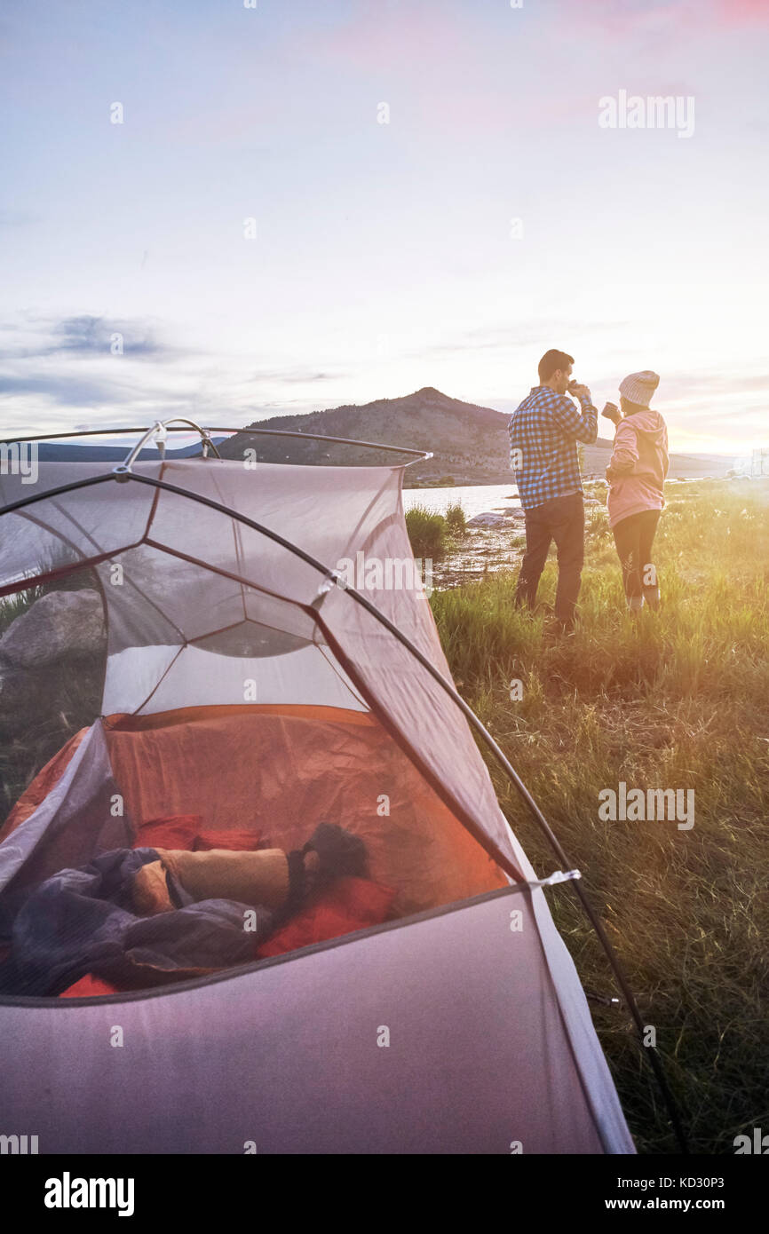 Paar in der Nähe von Zelt, trinken Sie heiße Getränke, in Aussicht, Heeney, Colorado, United States Stockfoto