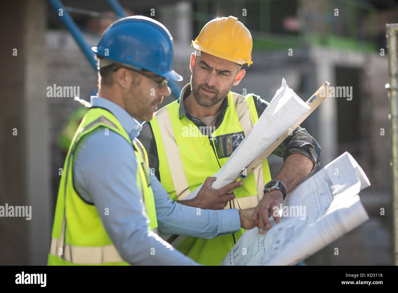 Projektleiter und Bauarbeiter mit Blick auf Pläne Stockfoto