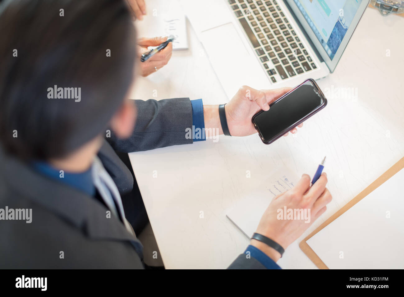 Geschäftsmann an Smartphone am Schreibtisch auf der Suche Stockfoto