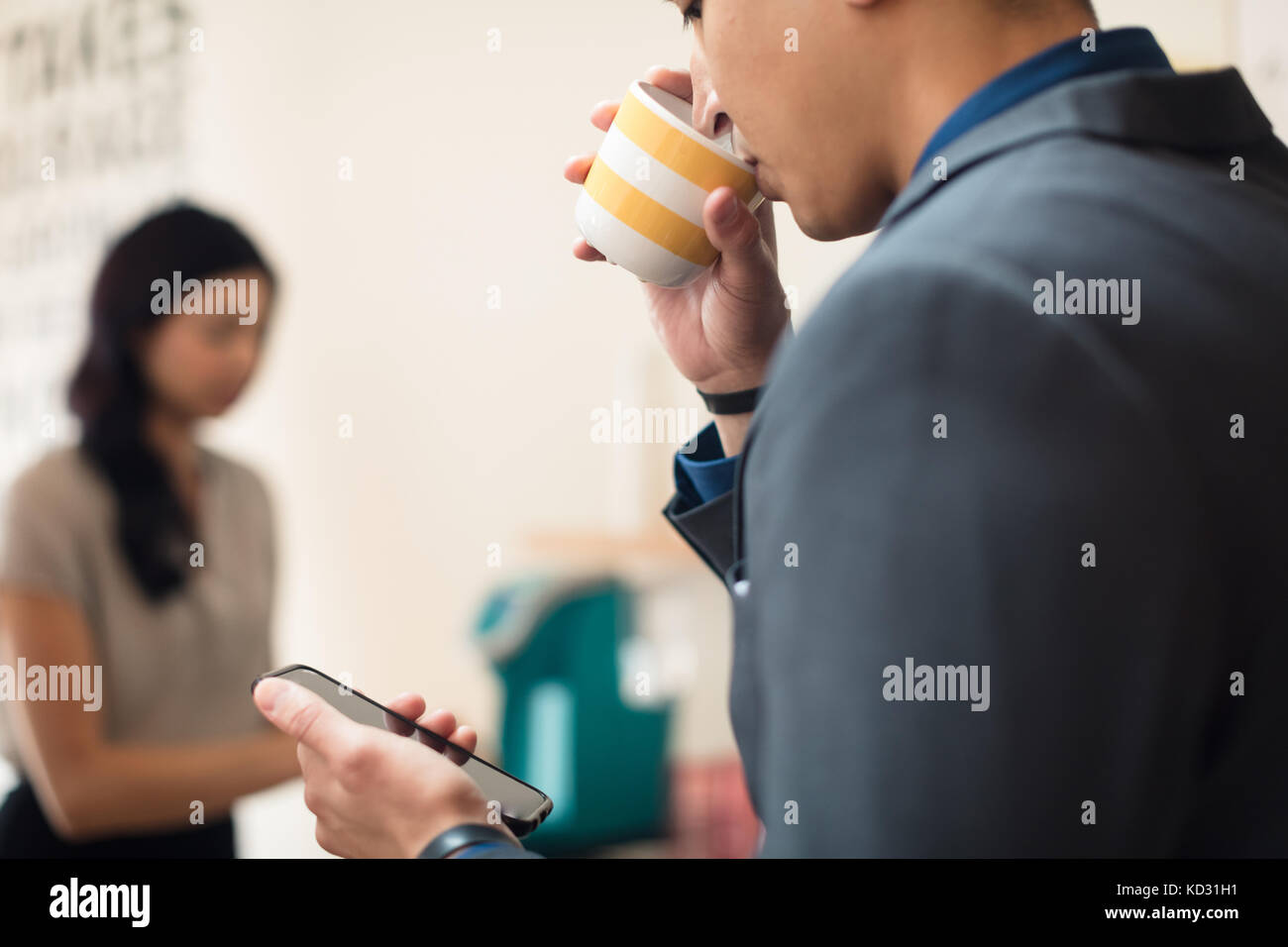 Junge Geschäftsfrau Blick auf Smartphone im Büro Stockfoto