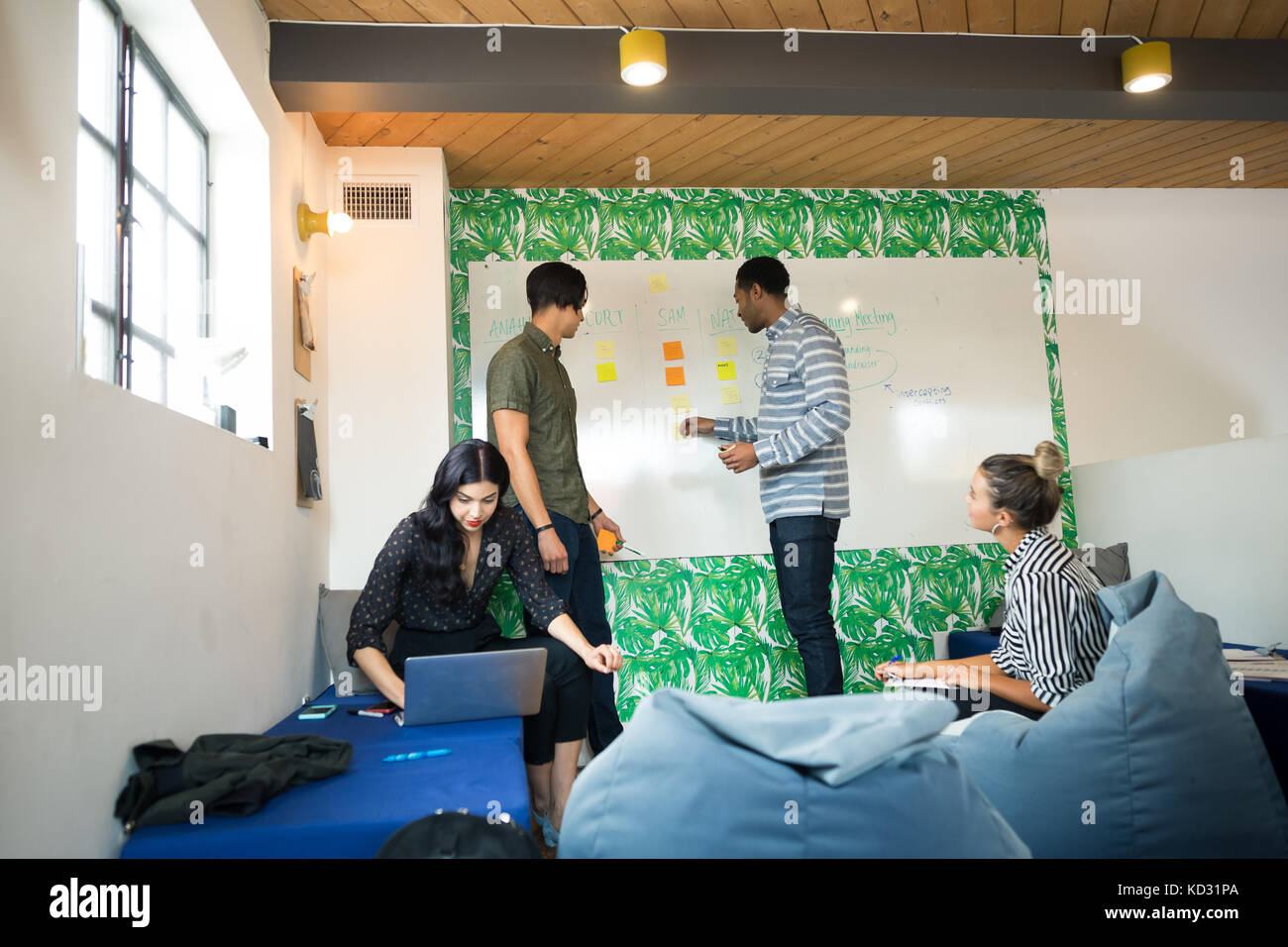 Junge Unternehmer und Frauen mit Laptop und Whiteboard in der kreativen Tagungsraum Stockfoto