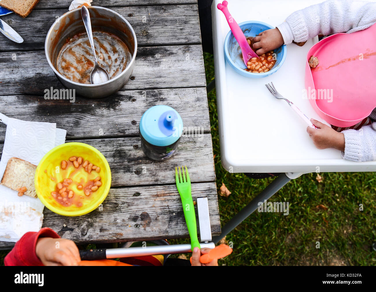 7/8-Ansicht von zwei Kleinkinder essen gebackene Bohnen auf dem Campingplatz Stockfoto