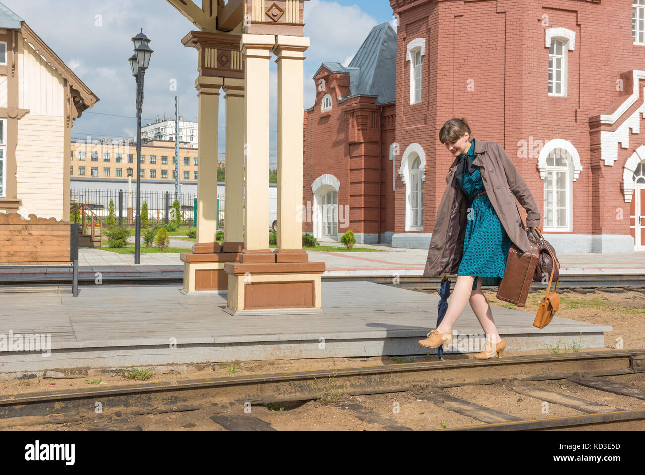 Junge Frau geht auf Schienen an einem Bahnhof mit Gepäck Stockfoto