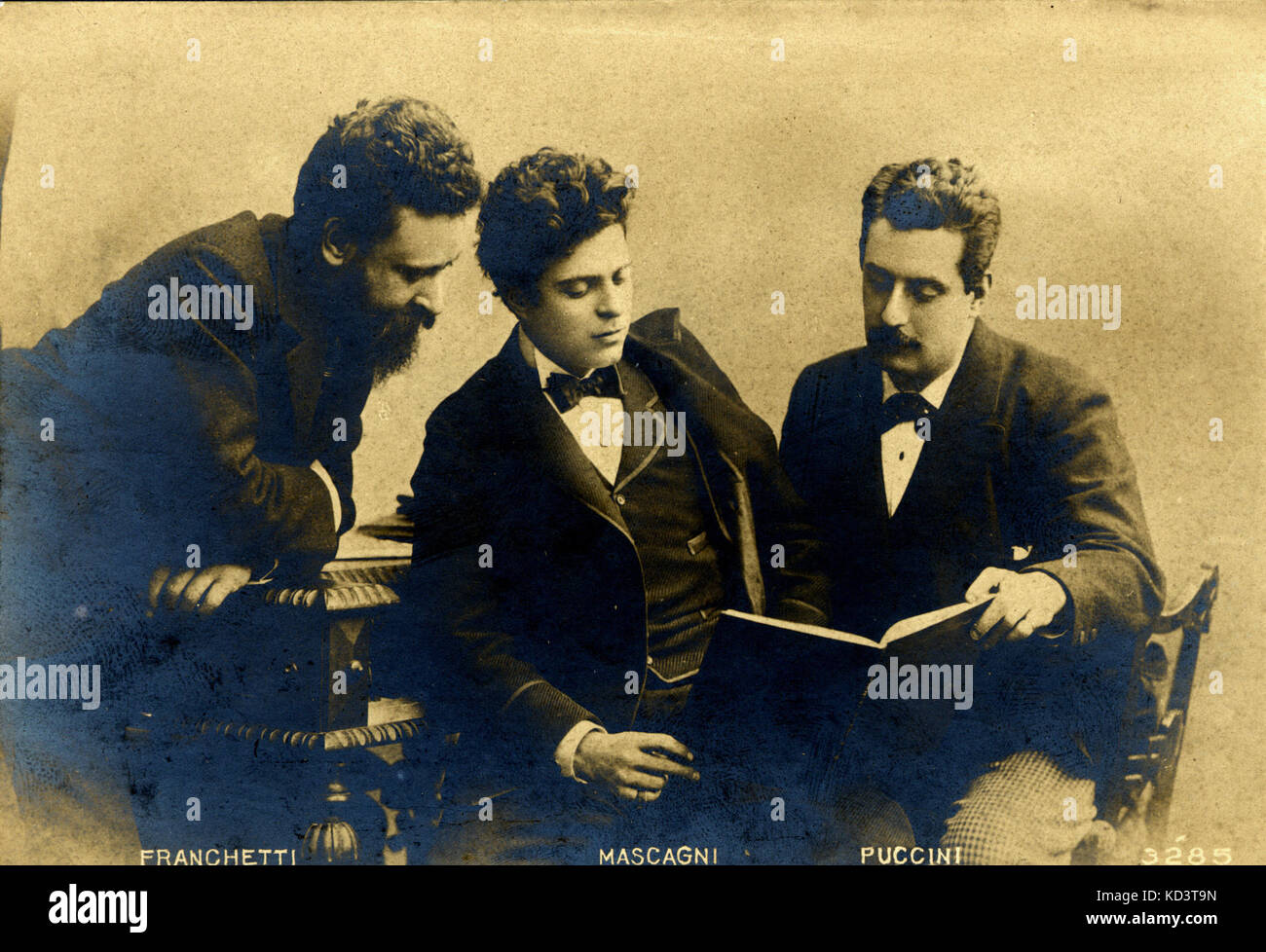 Giacomo Puccini, Pietro Mascagni & Alberto Franchetti. Die drei italienischen Opernkomponisten, der eine Partitur, sitzen um ein Klavier. Termine sind jeweils: 1858-1924, 1863-1945, 1860-1942. Stockfoto