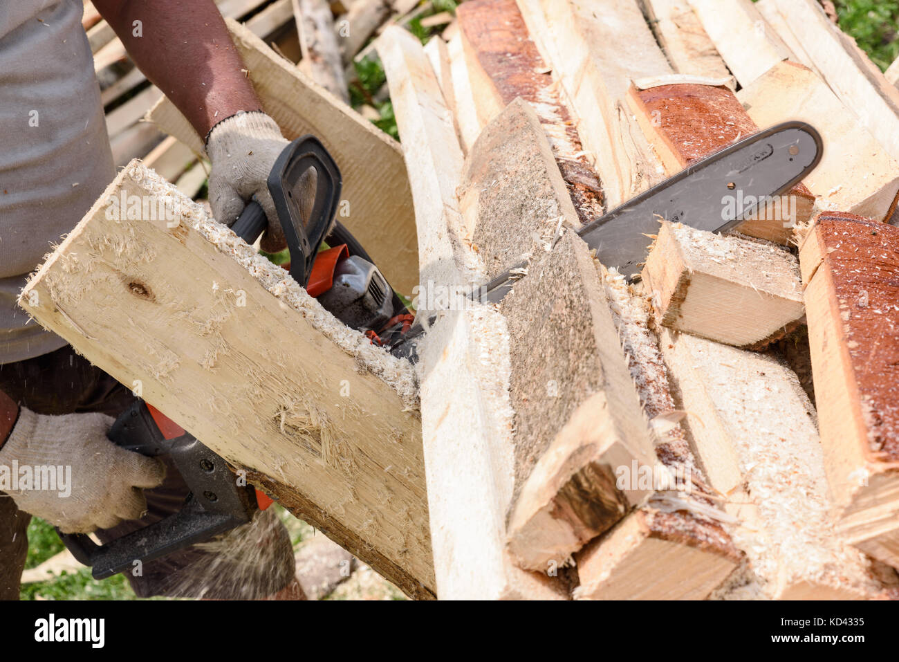 Mann sägt Holz mit orange Kettensäge Stockfoto