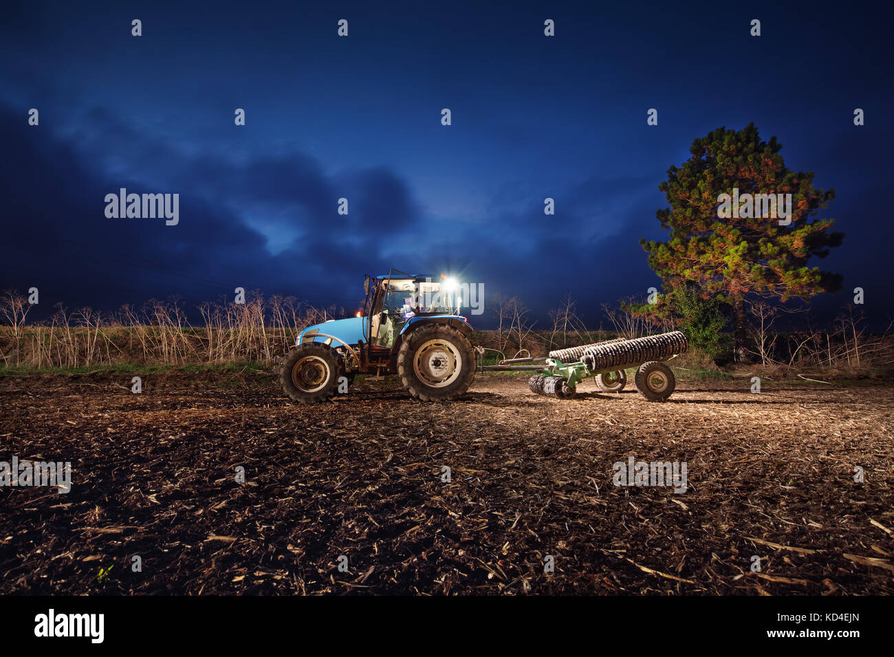 Traktor Vorbereitung land mit saatbeet Kultivator bei Nacht Stockfoto