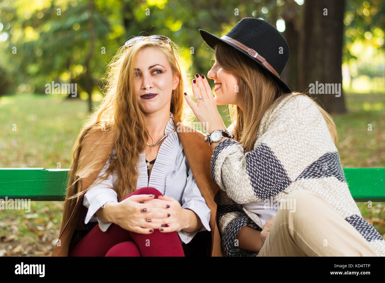 Weibliche Freunde klatschen auf einer Parkbank Stockfoto