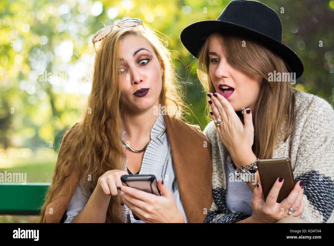 Weibliche Freunde klatschen mit einem Telefon im Park Stockfoto