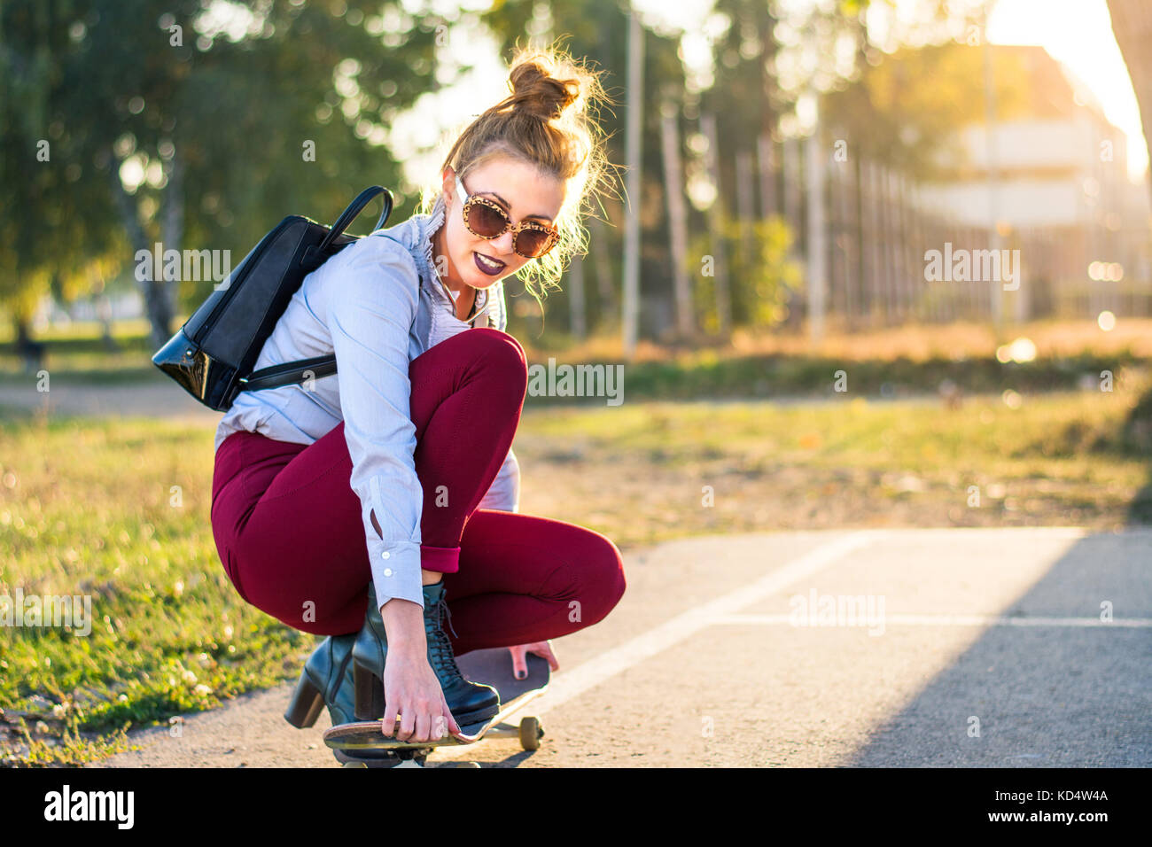 Modische Mädchen mit einem Skateboard im Park bei Sonnenuntergang Stockfoto